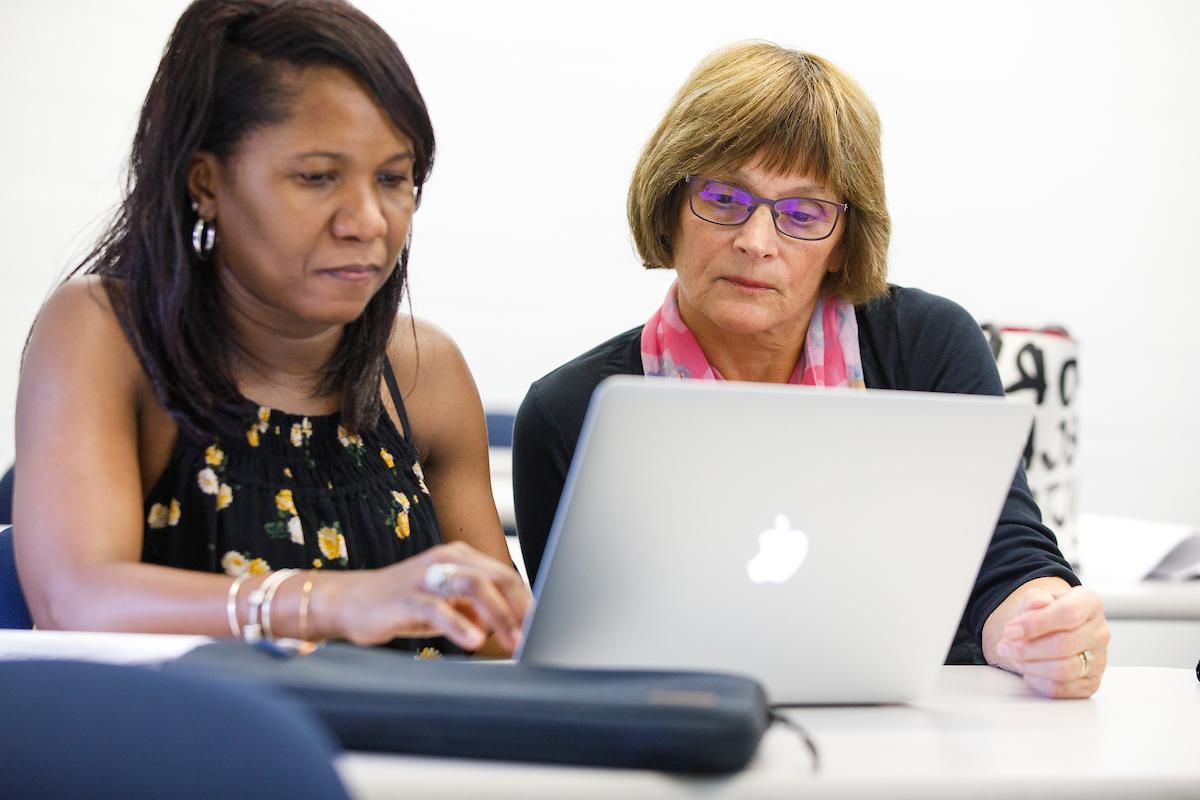 image is of a student and teacher looking at a laptop together