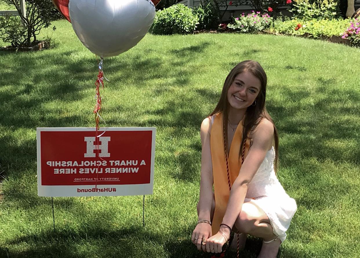 photo of Kyla next to her lawn sign announcing she's a winner of the tuition competition 