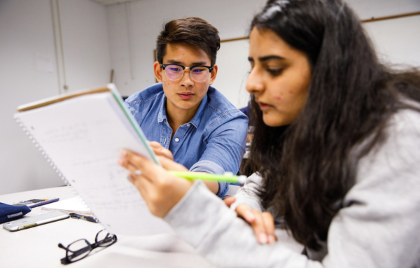 Two UHart students reviewing homework on a notebook.